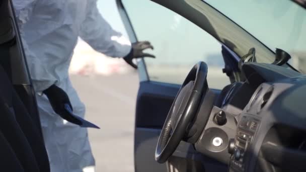 Hazmat team worker disinfects steering wheel with antibacterial sanitizer wipe on coronavirus covid-19 quarantine. Man in gas mask, hazmat suit cleans car interior with rag and sprayer washer. — Stock Video
