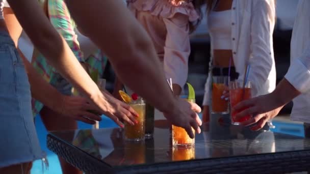 Bir grup arkadaş havuz başındaki yaz partisinde eğleniyor. Masadan renkli kokteyller alıyor ve gülerek kadeh tokuşturuyorlar. İnsanlar lüks tropikal villada yavaş çekimde taze meyve suyu içerek kadeh kaldırıyorlar.. — Stok video
