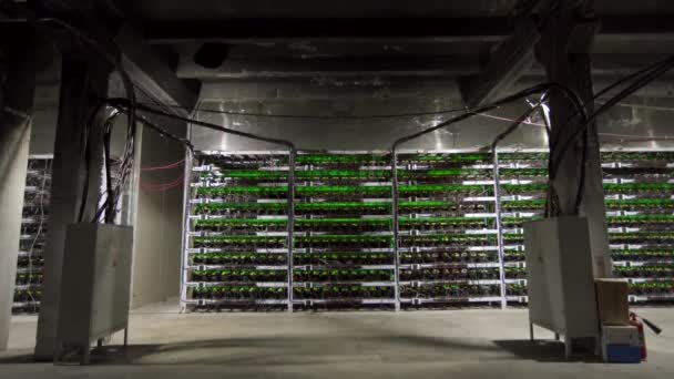 Large wired internet datacenter storage. Cryptocurrency mining equipment on large farm. ASIC miners on stand racks mine bitcoin in server room. Supercomputer blinking with lights. Tripod tilt. — Stock Video