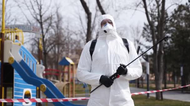 Travailleur chargé de l'enlèvement des matières dangereuses en combinaison de protection contre les matières dangereuses et masque facial avec équipement d'assainissement posé pendant l'éclosion du virus. Hero shot de l'homme en respirateur avec pulvérisateur. Coronavirus, COVID-19 . — Video