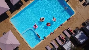 Havadan. Arkadaşlar şişme flamingo, kuğu, şamandıra ve şezlonglara bronzlaşırlar. Lüks otellerdeki şişme yataklarda banyo yapan mutlu gençler. Yukarıdan bak. Bikinili kızlar güneşte güneşleniyor.