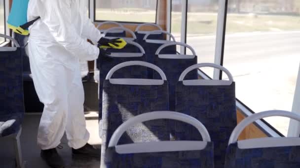 Hazmat team worker disinfects bus interior with antibacterial sanitizer wipes on coronavirus covid-19 quarantine. Man in gas mask, hazmat suit cleans public transport seats, handholds with rag. — Stock Video