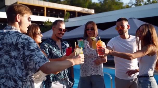 Група друзів, які розважаються на літній вечірці біля басейну, смердить окулярами з літніми коктейлями в сонячний день біля басейну. Люди тости п'ють свіжий сік на розкішній віллі на тропічних канікулах . — стокове відео