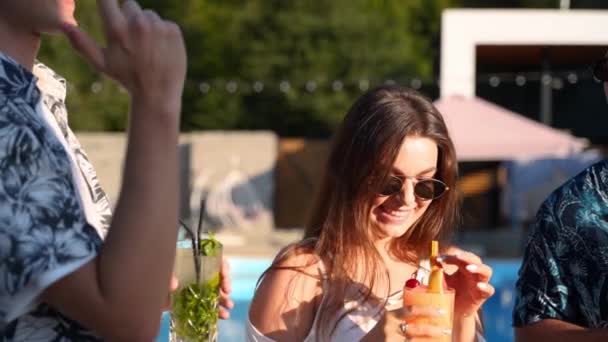 Bir grup arkadaş, havuz başında yaz partisinde bardakları tokuşturup güneşli bir günde havuz kenarında kokteyl içiyorlar. İnsanlar lüks tropikal villada yavaş çekimde taze meyve suyu içerek kadeh kaldırıyorlar.. — Stok video