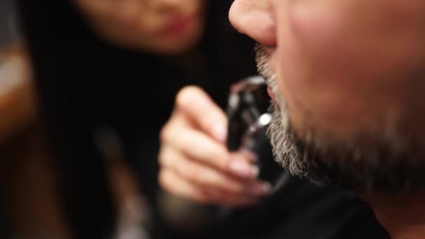 Frisör kvinna skär mans skägg med en trimmer i frisörsalongen. Män frisyr och hårklippning i salong. Grooming håret med clipper. Frisör gör frisyr i retro frisör. — Stockvideo