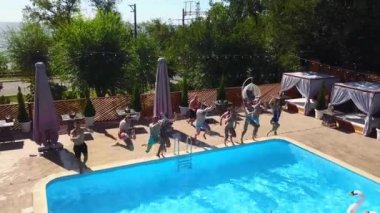 Lüks otellerde şişme şamandıralarla yüzme havuzunda zıplayan mutlu arkadaşlar. Mayolu gençler özel tatil köşkünde parti veriyorlar. Ateşli kızlar suya atlıyor. Yavaş çekim.