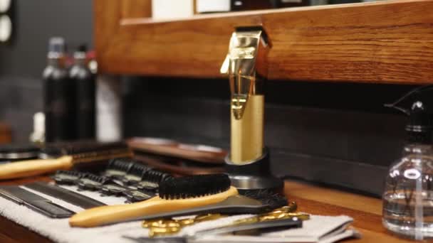Barber toma el moderno clipper inalámbrico de la estación de carga en la barbería. Mano de hombre recoge trimmer del cargador. Peluquería y herramientas de aseo en la mesa en el estudio: cepillos, tijeras, peines . — Vídeos de Stock