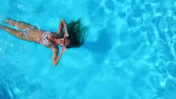 Aérea. Mujer nadando sobre su espalda en la piscina. Amigos enfriamiento con anillo inflable, colchón. Los jóvenes felices se bañan con juguetes flotantes en un resort de lujo. Vista desde arriba. Chica en bikini tomando el sol . — Vídeos de Stock