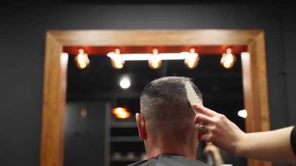 Kapper sproeit water op het haar van de klant voor het kapsel en styling in de kapperszaak. Kapster vrouw plast haar door spray en kamt ze in de kapsalon. Master gebruik waterspuit fles in mannelijke beauty studio. — Stockvideo