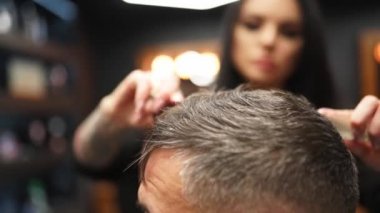 Çekici berber kız erkek saçını makas ve tarakla kesiyor. Müşteri hizmetinde çalışan kadın kuaför. Klasik berber koltuğunda oturan şık bir adam. Kuaför kadın moda saç kesimi yapıyor..