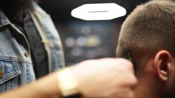 El peluquero moderno corta el cabello de los hombres barbudos con un cortador en la barbería. Para hombre peinado y corte de pelo en el salón. Aseo el cabello con trimmer. Peluquería haciendo corte de pelo en peluquería retro. — Vídeos de Stock