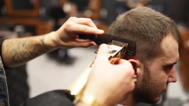 Barbeiro moderno corta barbudo homem cabelo com um cortador de cabelo na barbearia. Cabeleireiro masculino e corte de cabelo no salão. Arrumando o cabelo com aparador. Cabeleireiro fazendo corte de cabelo no salão de cabeleireiro retro. — Vídeo de Stock