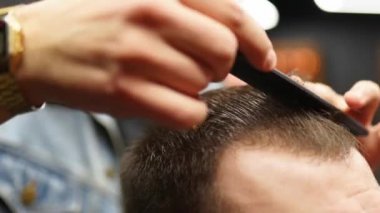 Berber adam adamın saçını makas ve tarakla kesiyor. Haircutter müşteriye hizmet ediyor. Klasik berber koltuğunda oturan şık bir adam. Kuaför moda saç kesimi yapıyor..