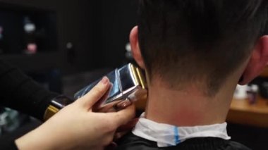 Çekici berber kız erkek saçını elektrikli traş makinesiyle kesiyor. Müşteri hizmetinde çalışan kadın kuaför. Klasik berber koltuğunda oturan şık bir adam. Kuaför kadın moda saç kesimi yapıyor..