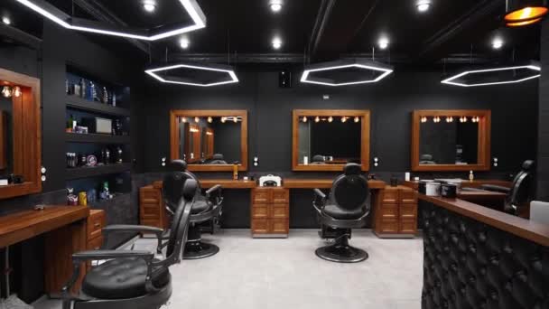 Interior de barbería vintage - movimiento a lo largo de las sillas, mesas de madera y espejos. Elegante estudio de cabello en el interior. Elegante diseño de salón de belleza con iluminación moderna y lámparas . — Vídeo de stock