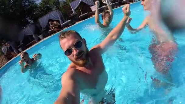 Lifestyle blogger man neemt selfie video met action camera in een zwembad. Reizen vlogger films vlog van partij op luxe resort. Fitted guy live streaming voor social media houdt van. Langzame beweging. — Stockvideo