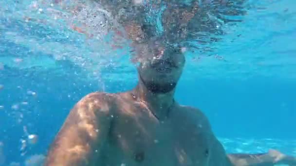 Lifestyle blogger man taking selfie video with action camera diving under water and having fun in swimming pool. Travel vlogger films vlog from party with friends at luxury resort. Slow motion. — Stock Video