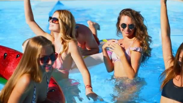 Amis ont piscine fête dansant avec matelas gonflable, pastèque jouets flottants. Les jolies jolies femmes chaudes en bikini et lunettes de soleil s'amusent à se détendre, se refroidissant le jour ensoleillé de l'été. Mouvement lent. — Video