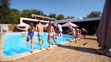 Lüks otellerde şişme şamandıralarla yüzme havuzunda zıplayan mutlu arkadaşlar. Mayolu gençler özel tatil köşkünde parti veriyorlar. Ateşli kızlar suya atlıyor. Yavaş çekim.