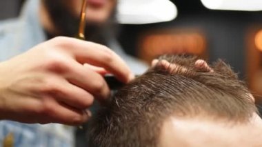 Berber adam adamın saçını makas ve tarakla kesiyor. Haircutter müşteriye hizmet ediyor. Klasik berber koltuğunda oturan şık bir adam. Kuaför moda saç kesimi yapıyor..