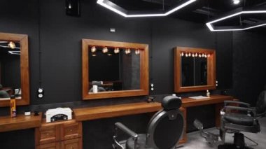 Klasik berber dükkanı iç mimarisi. Sandalyeler, ahşap masalar ve aynalar boyunca hareketlilik. Kapalı alanda şık bir kuaför. Modern ışıklandırma ve lambalar ile şık güzellik salonu tasarımı.