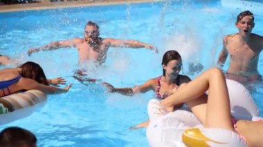 Arkadaşlar özel bir villada yüzme havuzunda parti yaparlar. Mayo giyen mutlu gençler su sıçratır, şamandıralarla dans eder ve güneşli bir günde lüks bir tatil köyünde şişme yatak giyerler. Yavaş çekim.