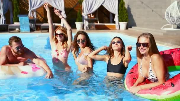 Friends have pool party dancing with inflatable mattress, watermelon floaty toys. Attractive hot pretty women in bikini and sunglasses have fun relaxing, chilling on sunny summer day. Slow motion. — Stock Video