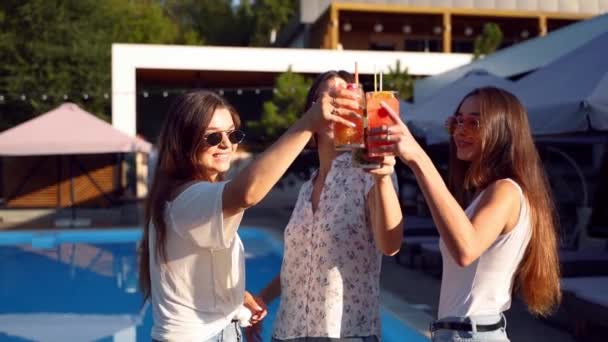 Group of girls having fun at summer pool party, clinking glasses with cocktails and dancing near hotel swimming pool outdoors. Women toast drinking juice at luxury villa in slow motion. — Stock Video