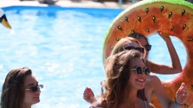 Arkadaşlar özel bir villada yüzme havuzunda parti yaparlar. Güneşli bir günde mayo giyen, dans eden, şamandıralarla takılan ve lüks bir tatil köyünde şişme yatak giyen mutlu gençler. Yavaş çekim.