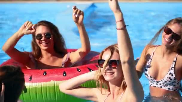 Przyjaciele mają imprezę w prywatnym basenie willi. Szczęśliwi młodzi ludzie w strojach kąpielowych tańczą, łączą się i klubują z platformami i dmuchanym materacem w luksusowym kurorcie w słoneczny dzień. Zwolniony ruch. — Wideo stockowe