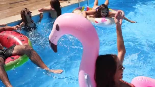 Vrienden hebben een feestje in een privé villa zwembad. Vrolijke jongeren in zwemkleding spetterend water, dansen met drijvers en opblaasbare matrassen in luxe resort op zonnige dag. Langzame beweging. — Stockvideo