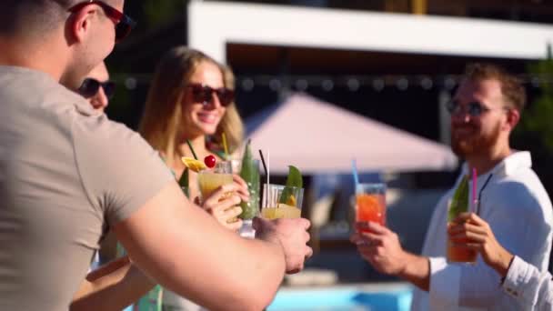 Vriendengroep die zich vermaken bij zwembad zomerfeest klinkende glazen met zomercocktails op zonnige dag in de buurt van zwembad. Mensen proosten vers sap in luxe tropische villa in slow motion. — Stockvideo