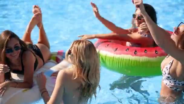 Friends have party in a private villa swimming pool. Happy young people in swimwear dancing, bonding and clubbing with floaties and inflatable mattress in luxury resort on sunny day. Tracking shot. — Stock Video