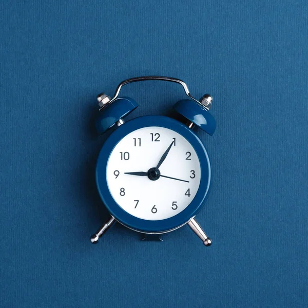 Relógio de alarme no fundo azul escuro . — Fotografia de Stock