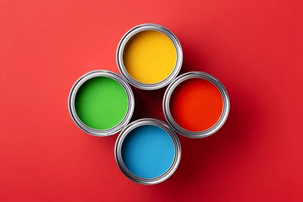 Latas de pintura colorida sobre fondo rojo . — Foto de Stock