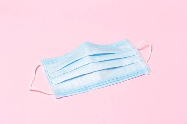 Pembe arka planda mavi tıbbi maske. Virüs kavramına karşı koruma.