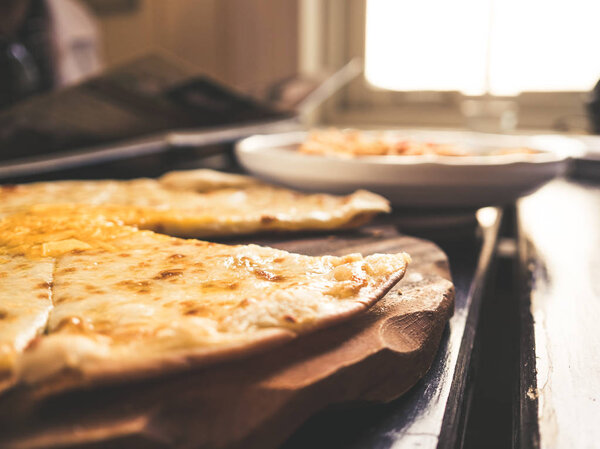 Delicious cheese pizza on classic wooden plate.
