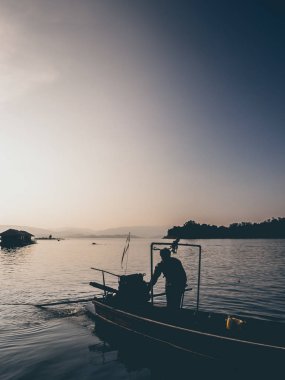 Gün batımı göl ve adam ve motorlu tekne silüeti.