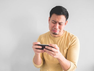 Asya adam ağlıyor onun smartphone telefon oyunda kaybediyor.