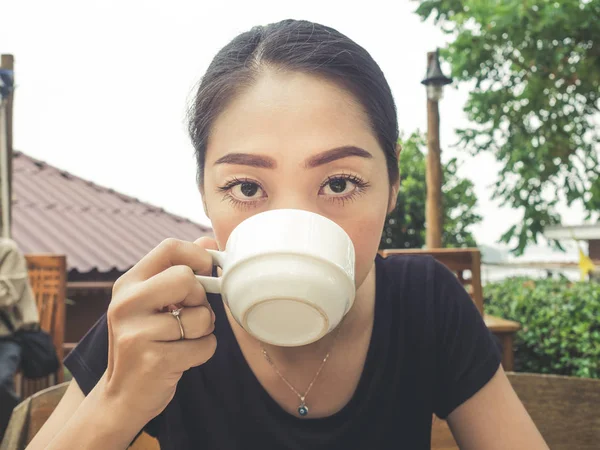 Asian woman drink coffee in breakfast lobby room of a resort.