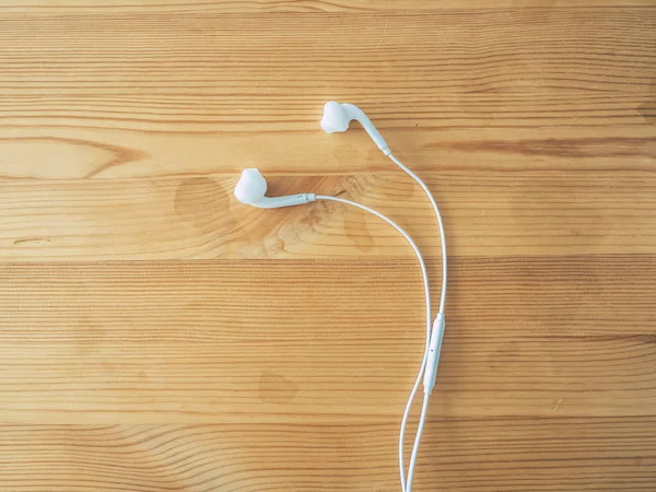 White earphone for smartphone on wooden table.