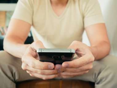 Adam oturmak ve smartphone kafede kullanın.