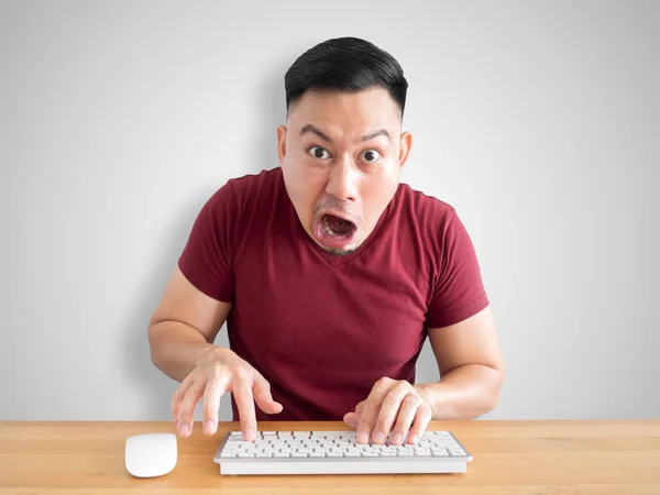 Shock and wow face of Asian man sit on his desk working in the office.