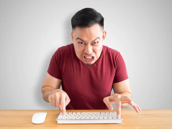 Angry and furious face of Asian man working with computer in the office.