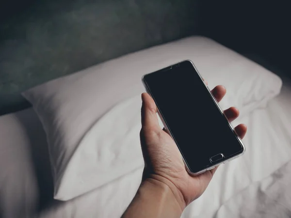 Man using smartphone on the bed at night.