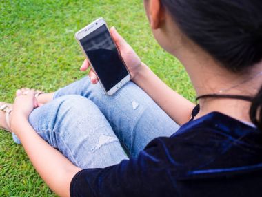 Asyalı kadın cep telefonuyla çim çim.