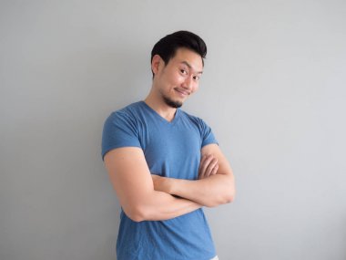 Gülümseme ve mavi t-shirt ve gri arka planda mutlu adam.