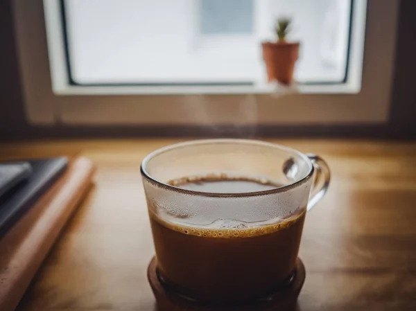 Cangkir kopi panas di atas meja dalam kondisi cahaya rendah di dekat jendela — Stok Foto