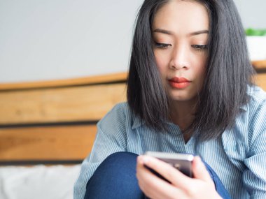 Yalnız Asyalı kadın odaya Smartphone kullanarak.