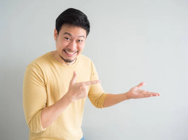 Uomo in t-shirt gialla entusiasta di puntare e presentare uno spac vuoto — Foto Stock